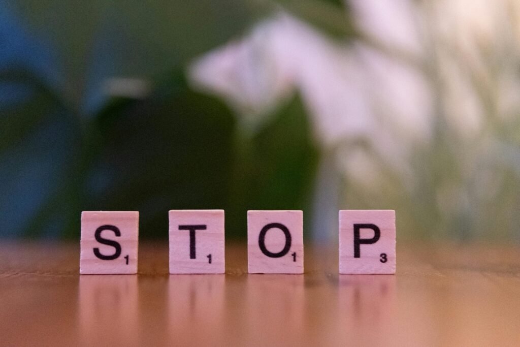 Close-up of Scrabble tiles spelling STOP on wooden table.